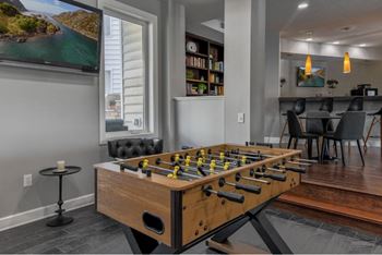 A foosball table is in the middle of a room with a TV and a dining area.
