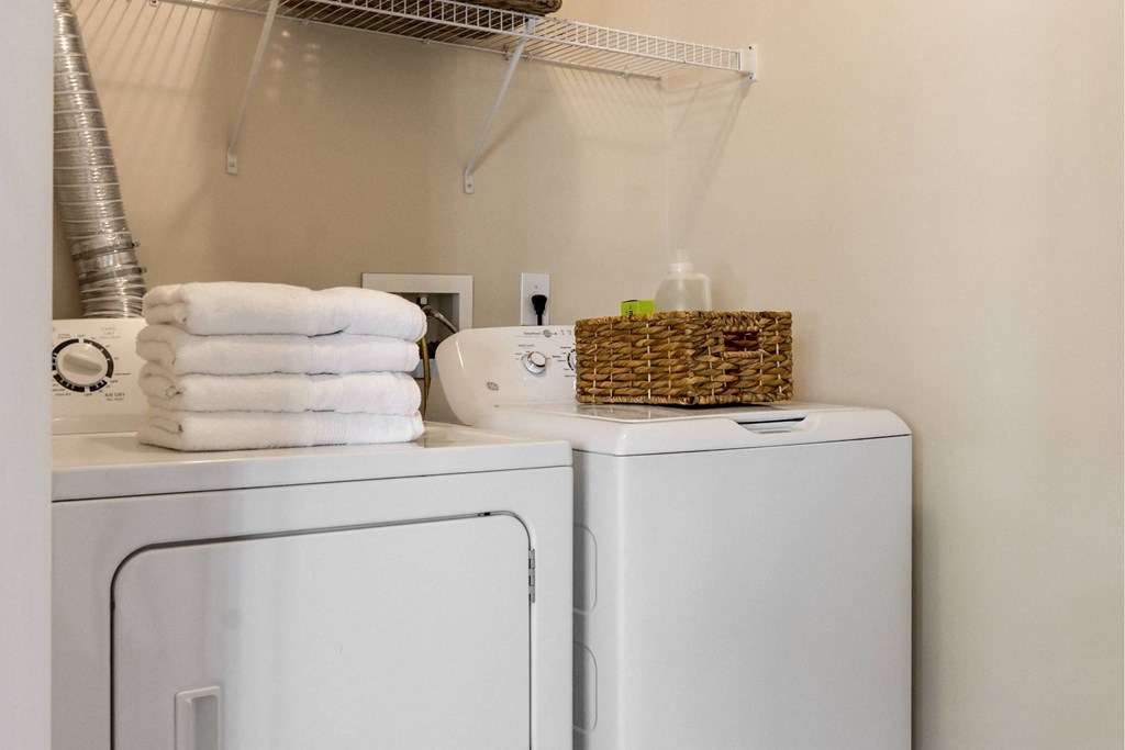 A white washing machine and dryer with towels on top of the dryer.