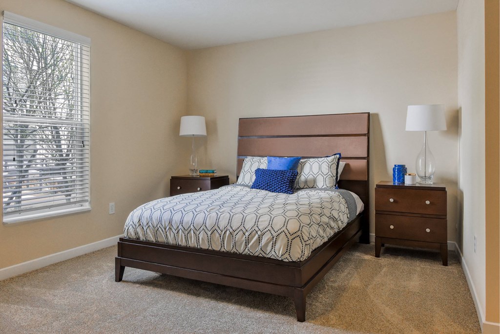 A bedroom with a bed, nightstands, and lamps.