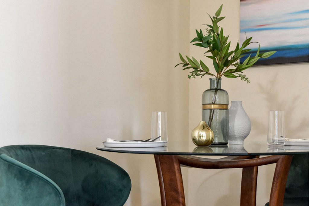A table with a vase, glasses, and a plant on it.