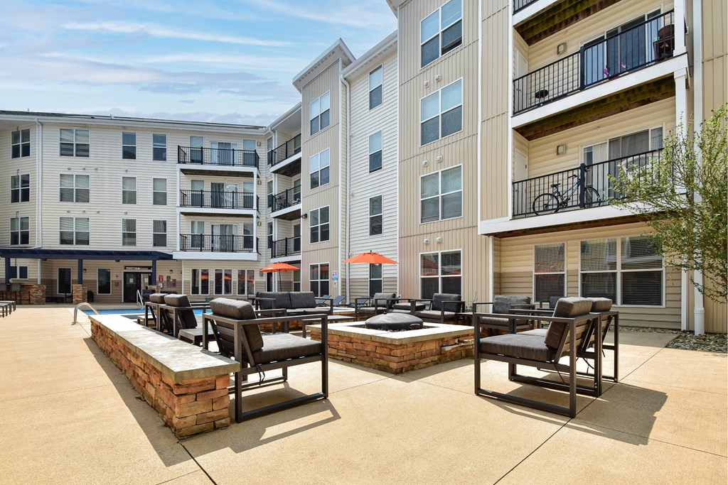A sunny day at a poolside with chairs and a building in the background.
