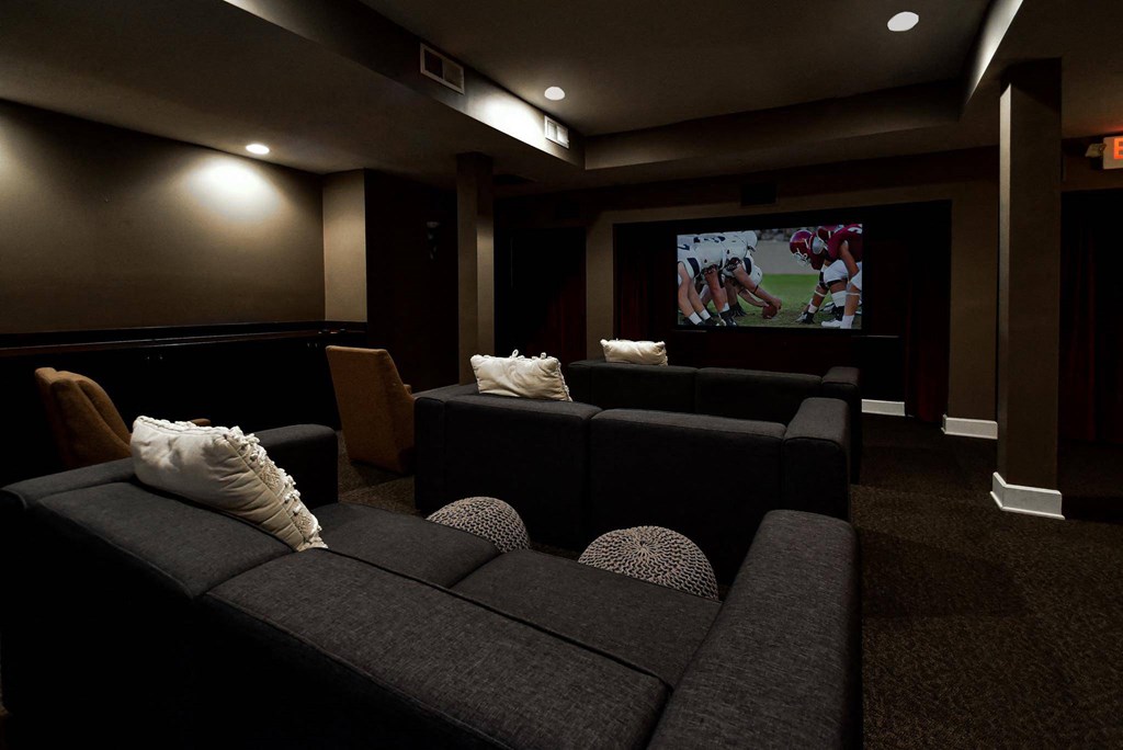 A dark room with a large screen and comfortable seating.