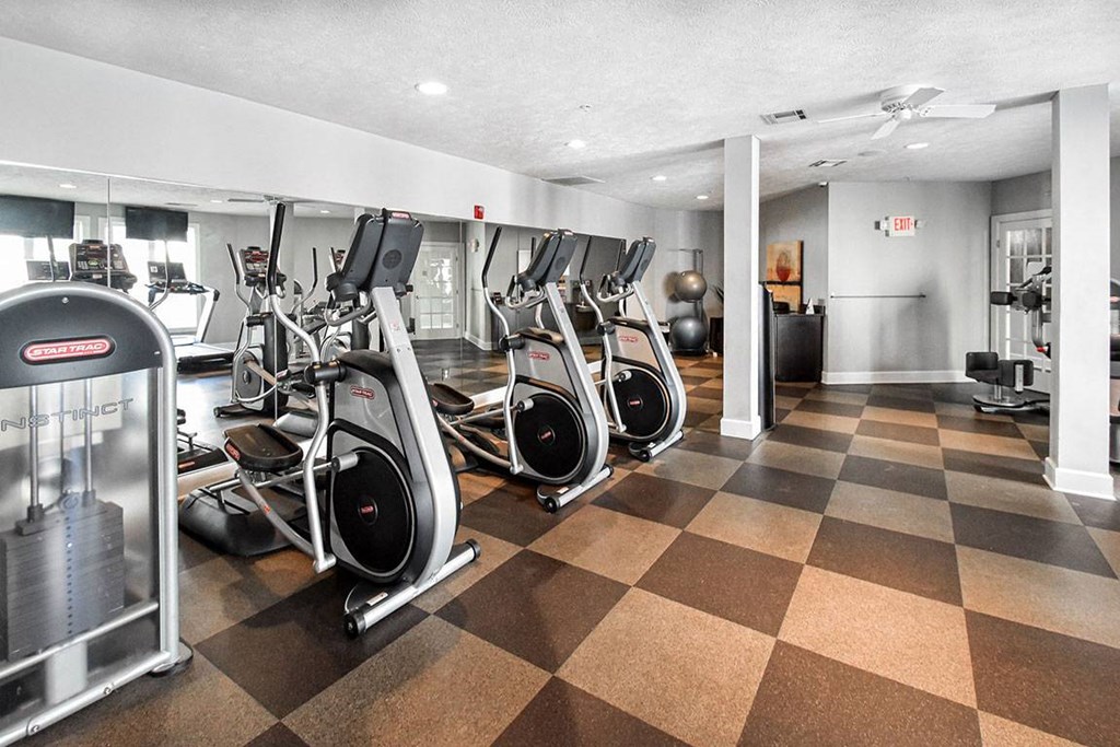 A gym with a variety of exercise equipment including treadmills, stationary bikes, and elliptical machines.