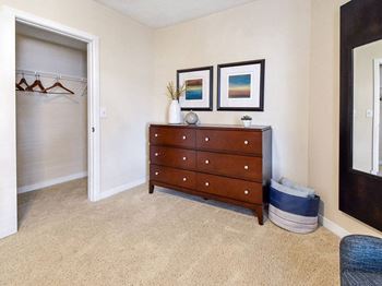 A room with a wooden chest of drawers and two pictures on the wall.