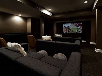 A dark room with a couch and a television playing a football game.