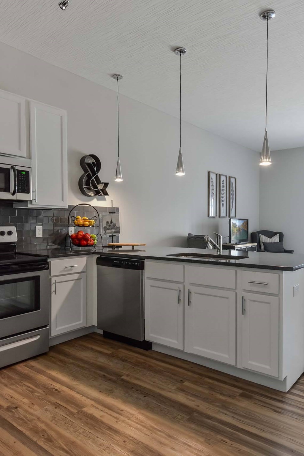 A modern kitchen with wooden floors and stainless steel appliances.