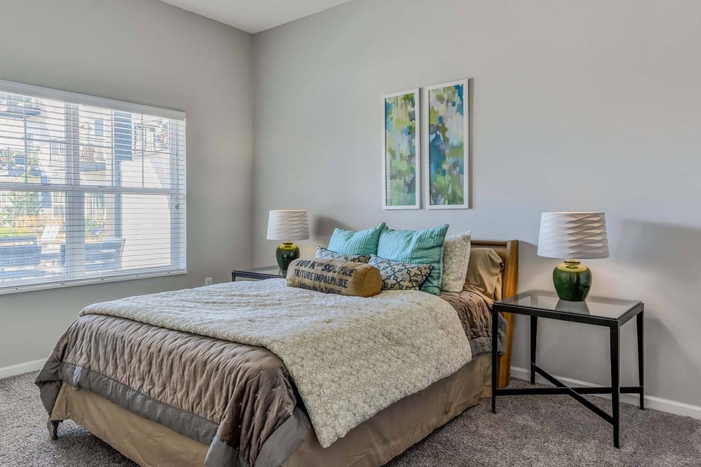 a bedroom with a bed and two lamps and a window