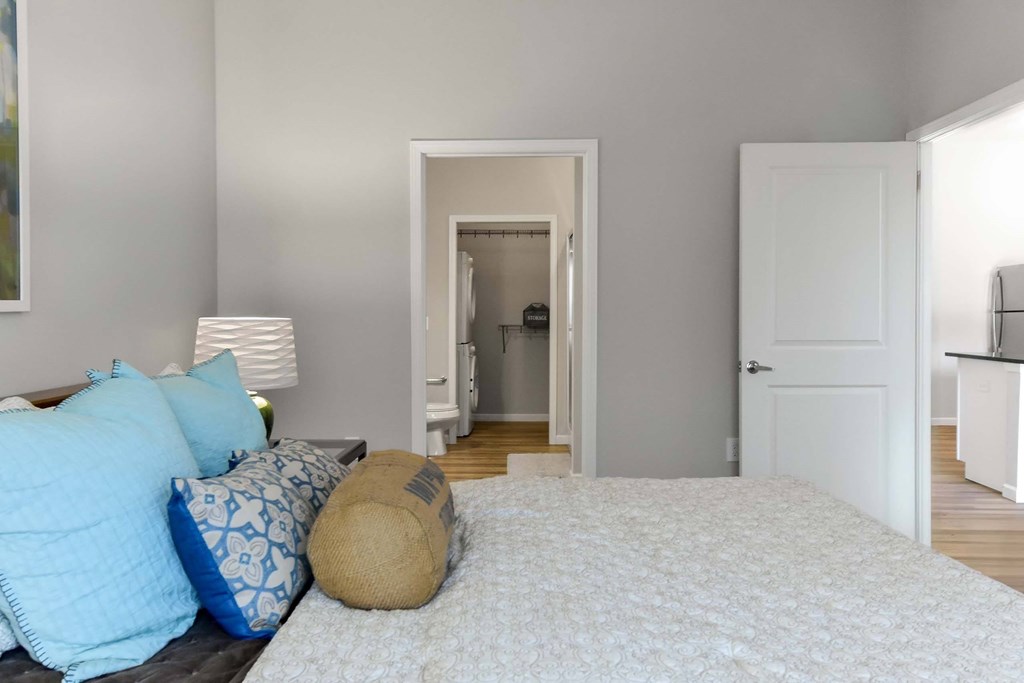 A bedroom with a bed, pillows, and a lamp.