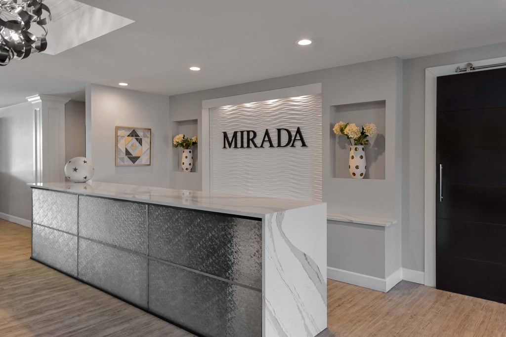 A reception area with a white reception desk and a wall with a framed picture and a vase of flowers.
