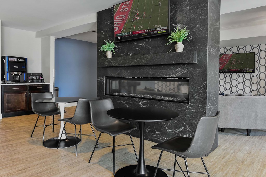 A black table with four chairs in front of a fireplace.