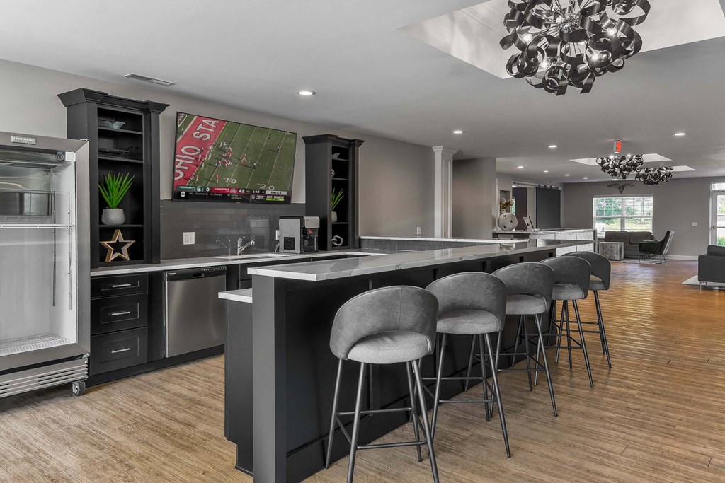 A modern kitchen with a large island and grey bar stools.