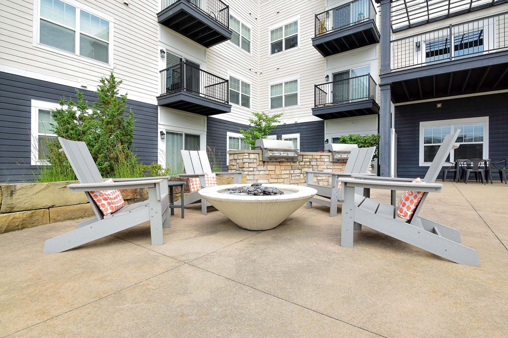A patio with a fire pit and chairs.