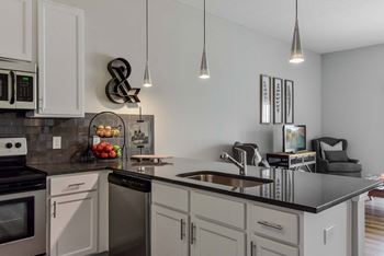 A modern kitchen with a black countertop and stainless steel appliances.