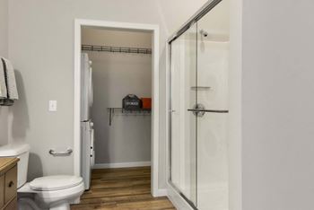 A white toilet is in a small bathroom with a walk-in shower.