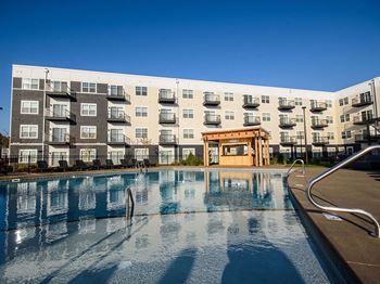 A large swimming pool in front of a multi-story apartment building.