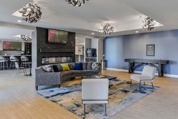 A modern living room with a grey couch, a white chair, and a TV mounted on the wall.