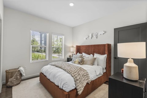 A bedroom with a large bed and a lamp on a side table.