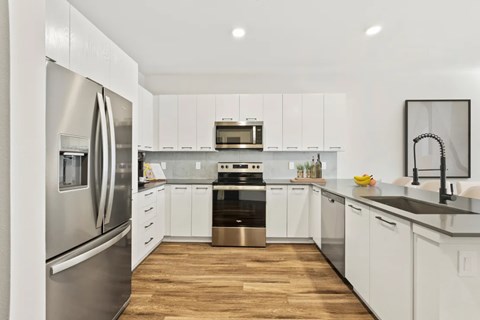 A modern kitchen with white cabinets and stainless steel appliances.