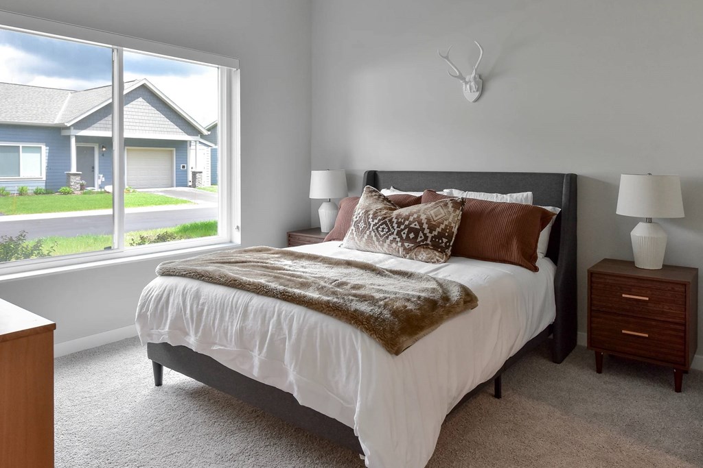 A bedroom with a large bed and a window overlooking a house.