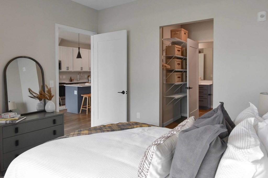 A bedroom with a white bed and a mirror on the dresser.
