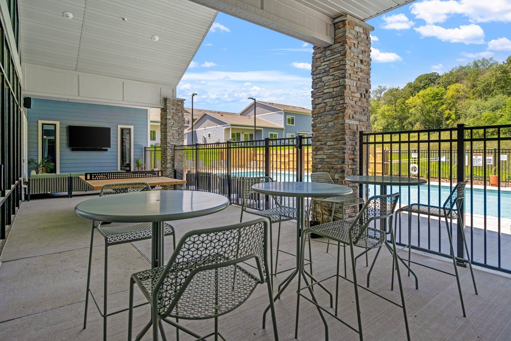 A patio with a table and chairs overlooking a pool.