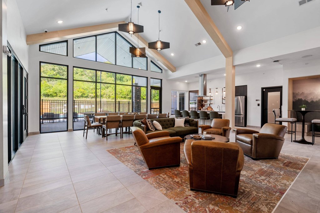 A living room with a glass wall and brown leather chairs.