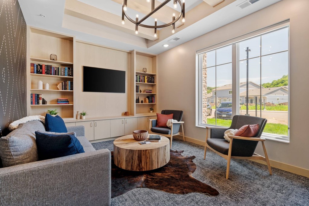 A living room with a grey couch, a wooden coffee table, and a large window.