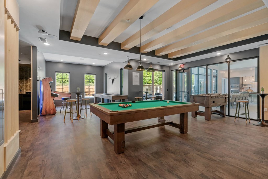 A billiard table is in the middle of a room with a wooden floor and ceiling.