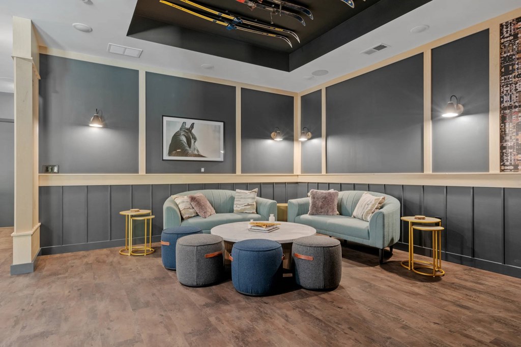 A modern living room with a grey sofa, a round table, and a grey ottoman.