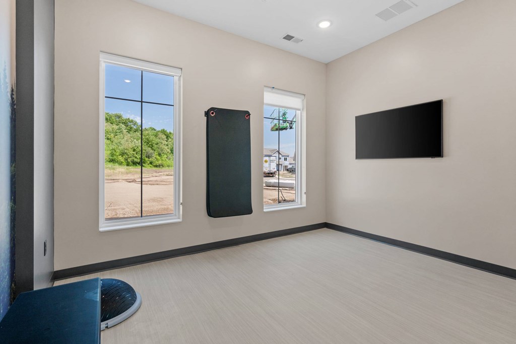 A room with a large window, a smaller window, and a flat screen TV mounted on the wall.