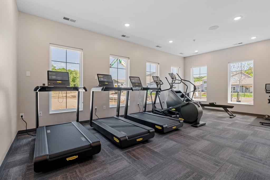 A spacious gym with treadmills, elliptical machines, and a stationary bike.