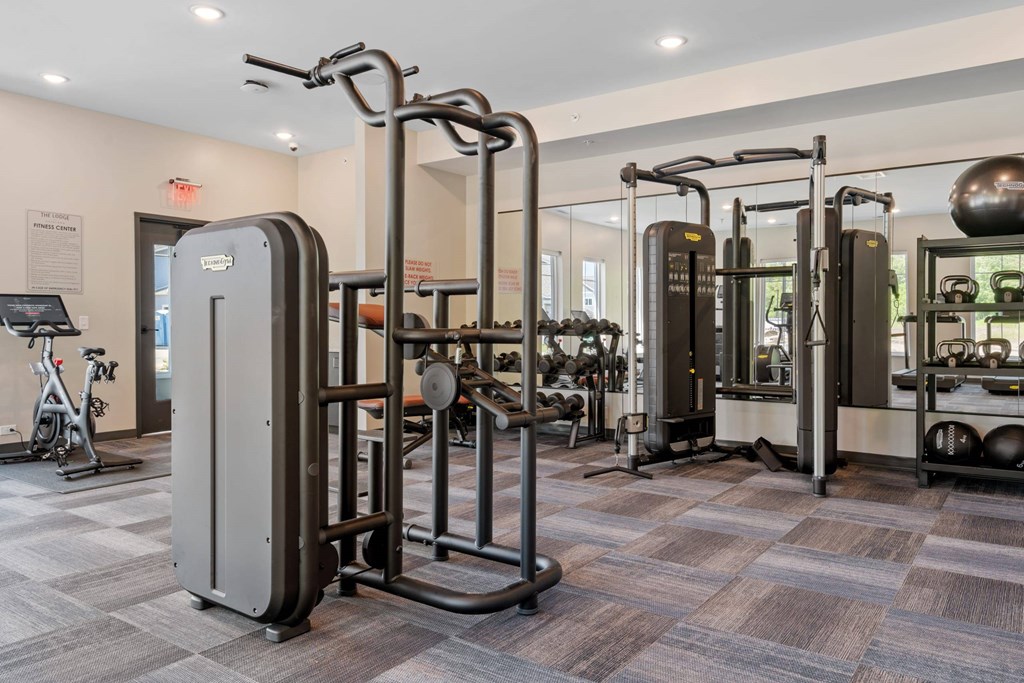 A gym with a variety of equipment including a treadmill, weights, and a stationary bike.
