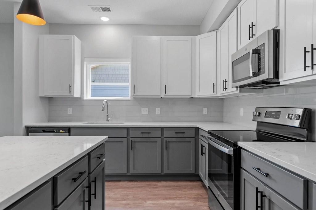 A kitchen with white cabinets and black appliances.