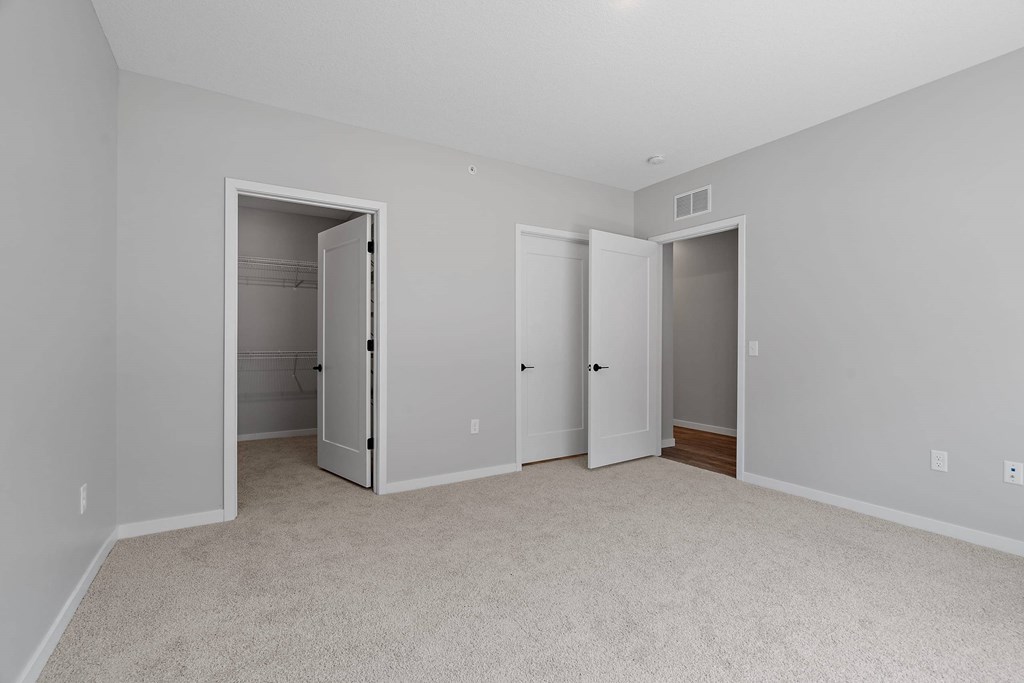 A room with three doors and carpeted flooring.