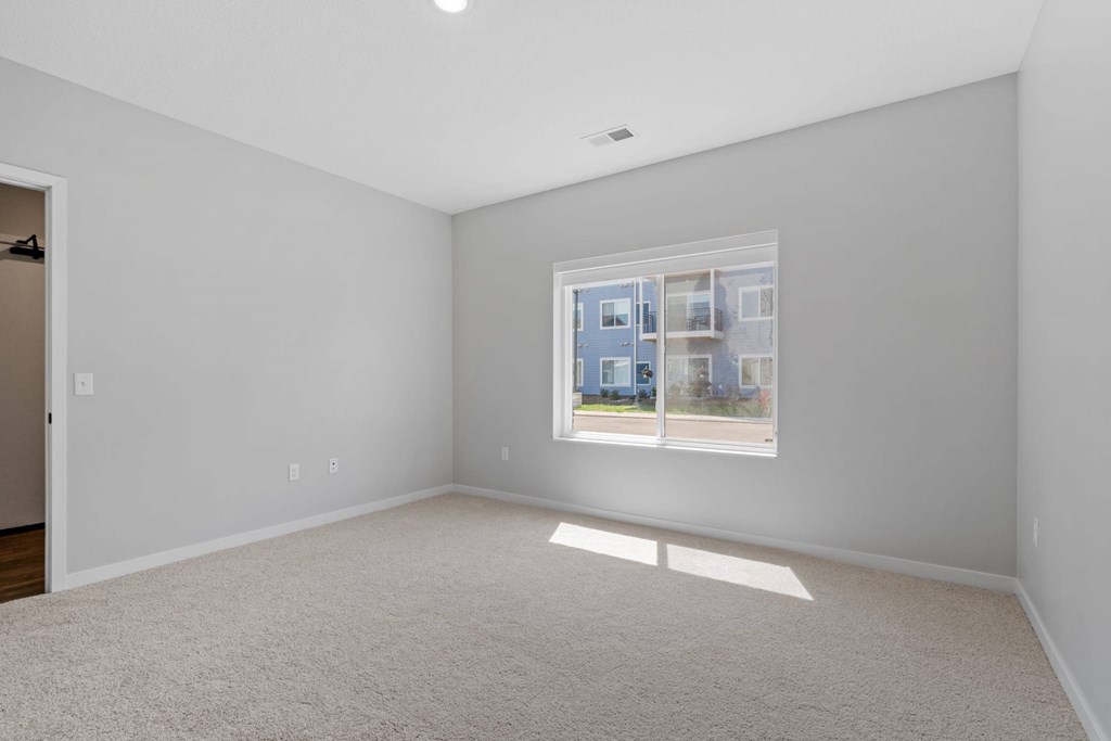 A room with a window showing a view of a building outside.