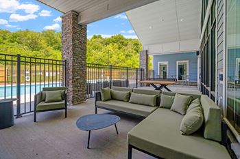 A patio with a table and chairs overlooking a pool.