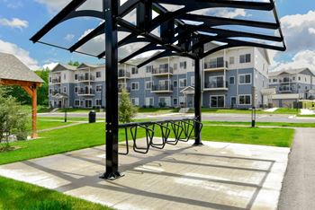 A black metal structure is in the foreground of a sunny day with apartment buildings in the background.