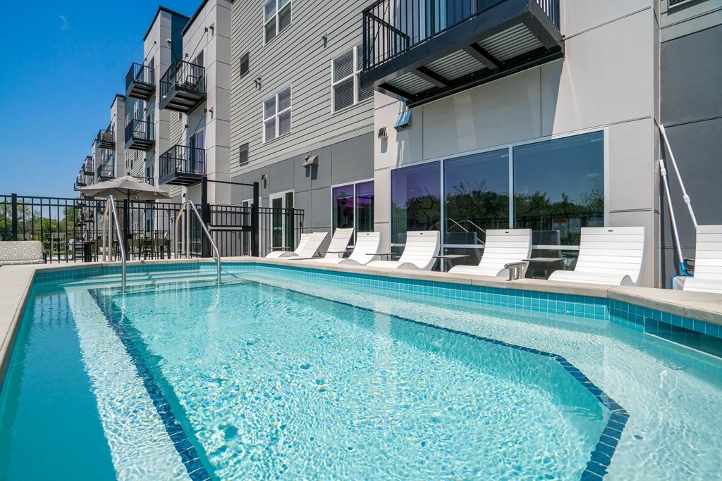 A swimming pool in front of a modern apartment building.