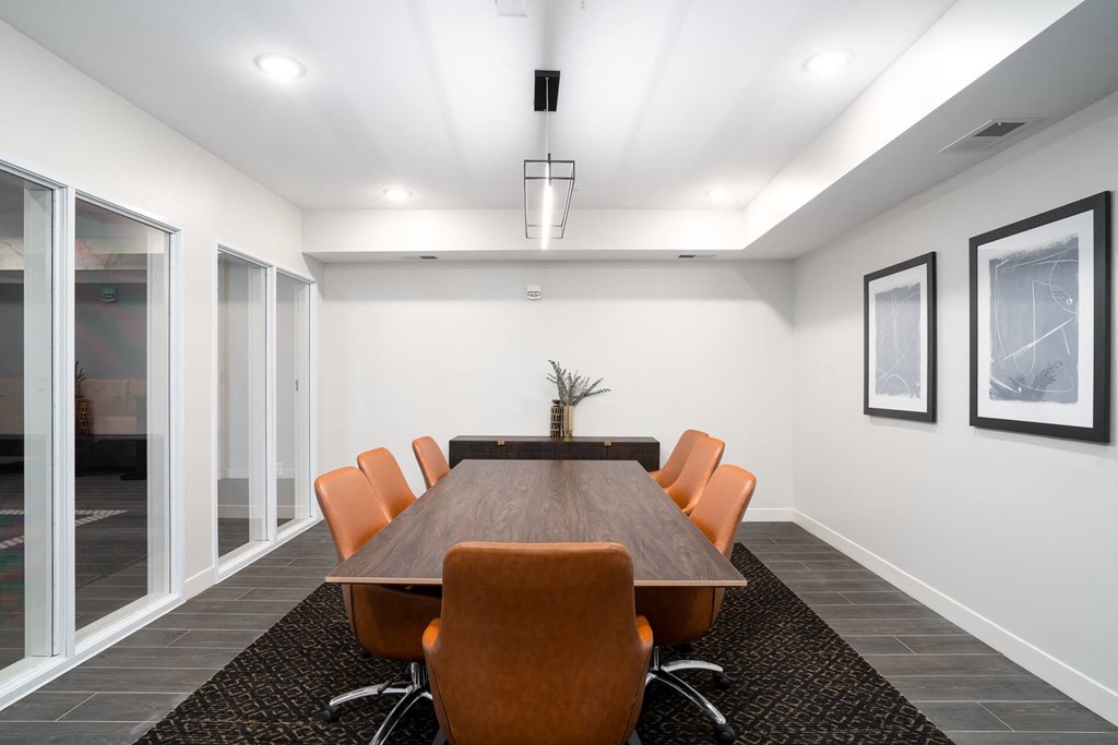 A conference room with a long table and orange chairs.