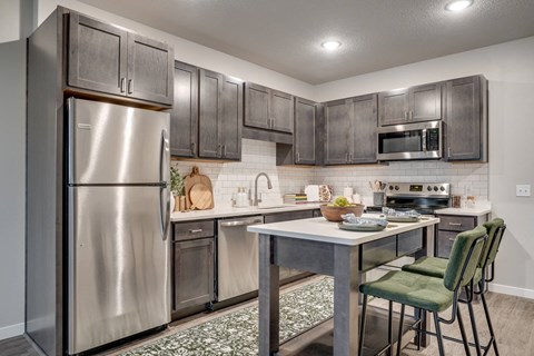 A kitchen with a stainless steel refrigerator and a table with chairs.
