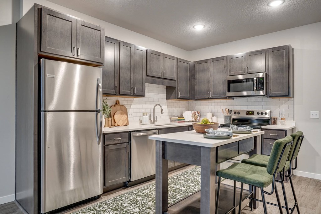 A kitchen with a stainless steel refrigerator and a table with chairs.