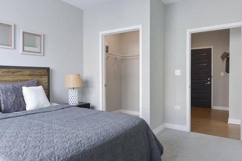 A bedroom with a bed, lamp, and two doors.
