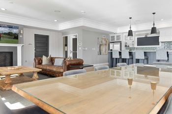 A modern living room with a glass table and leather couches.