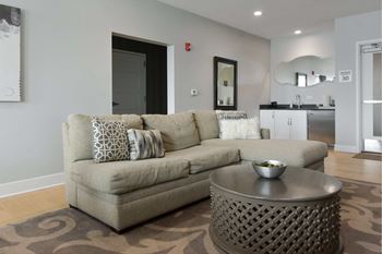 A grey couch with pillows sits in a living room with a coffee table in front of it.