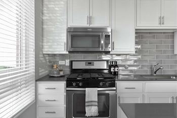 A modern kitchen with white cabinets and a black stove top.