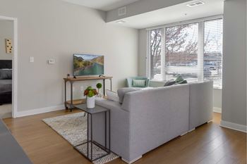 A living room with a grey couch and a painting on the wall.