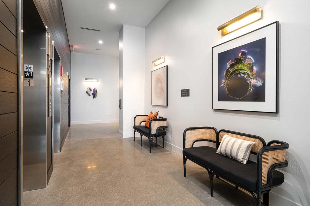 A hallway with a bench, a painting, and a framed picture on the wall.