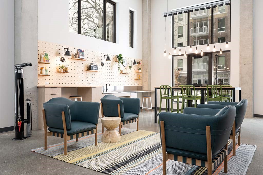 A room with a row of chairs and a wall with shelves and plants.