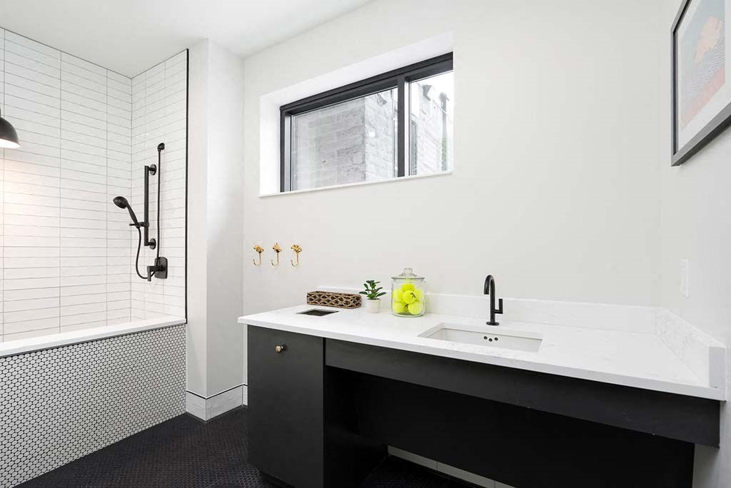 A bathroom with a black and white theme featuring a sink, a mirror, and a shower.