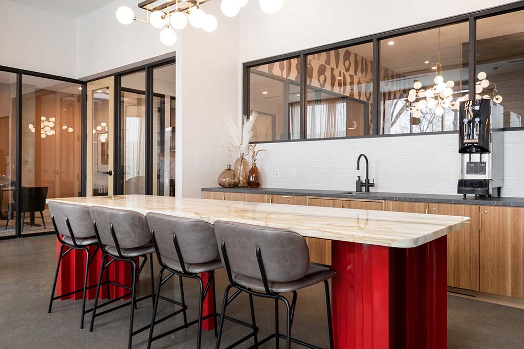 A modern kitchen with a long island and chairs.